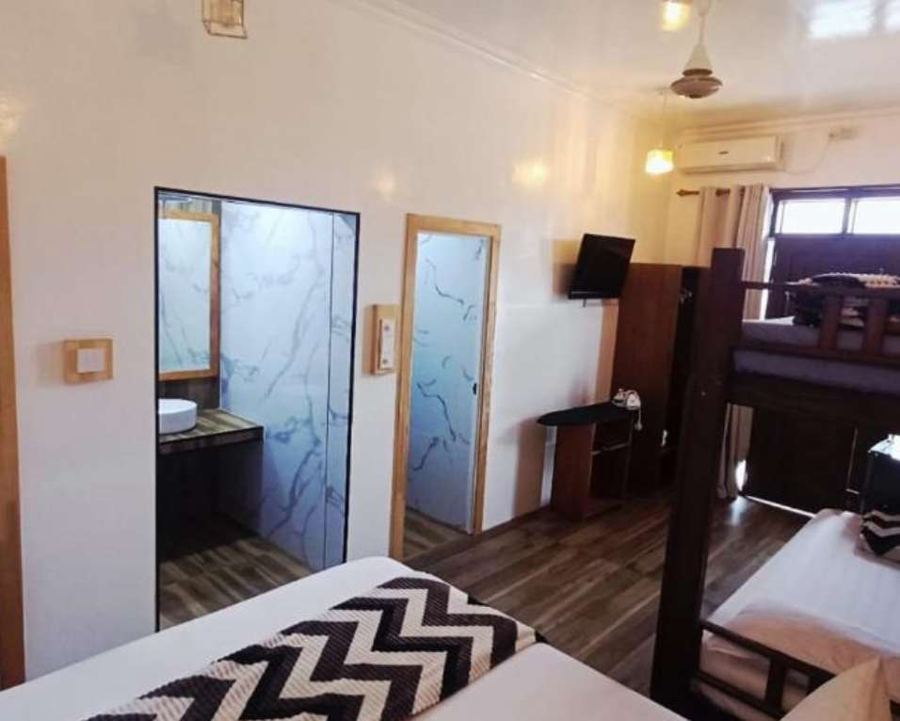 Family room seen from the bed, with frosted glass bathroom doors, wooden floor and the bunk bed