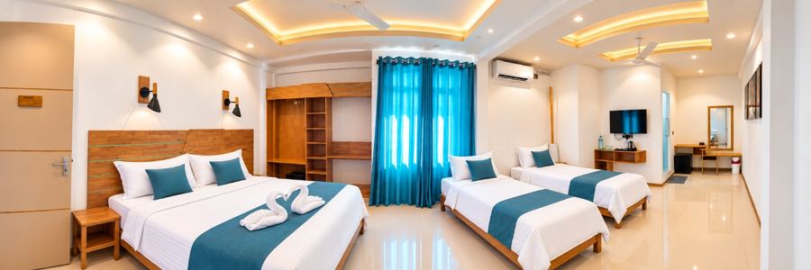 Wide view of a large room with a double bed and two single beds, blue curtains and wooden furniture