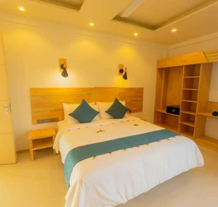 Suite bedroom with an extra-large double bed decorated with flowers, warm lighting and open wooden shelving