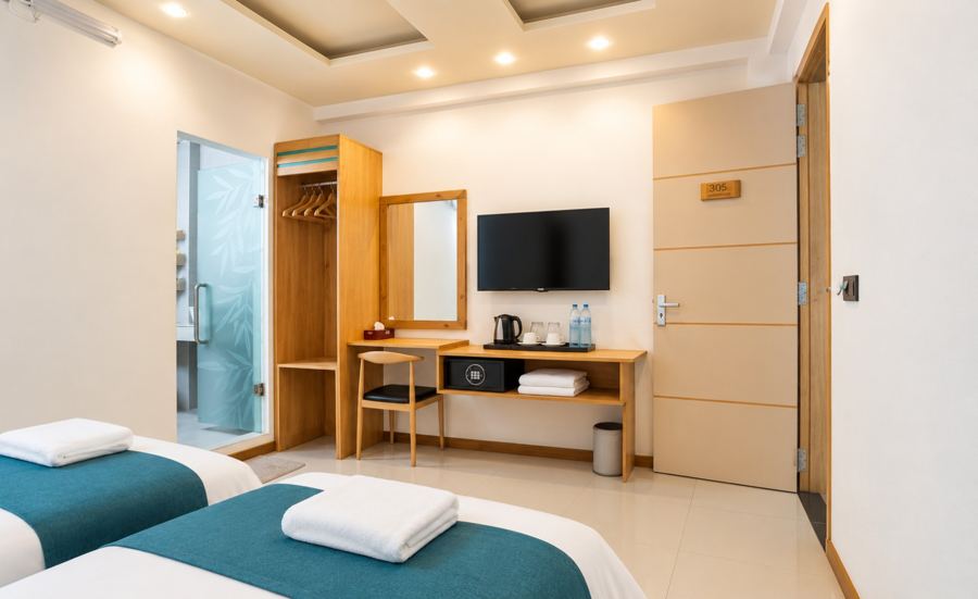 Wooden desk with a mirror, wall TV, kettle and wardrobe, with the beds in front
