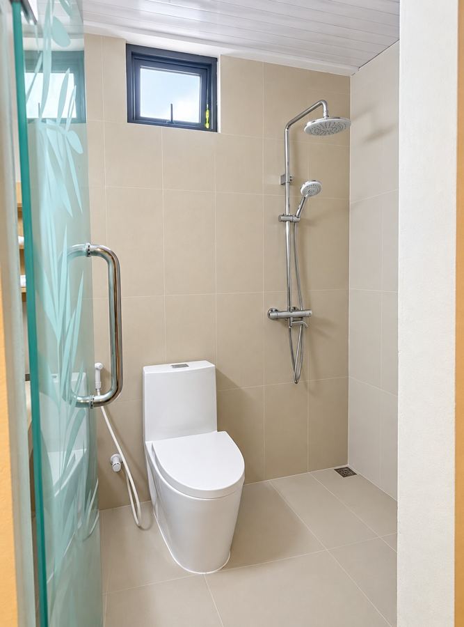 Bright shower room with a glass door, rain shower and toilet