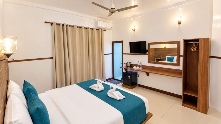 Bedroom with a large bed in white and teal, dark wood trim, wall-mounted TV, mirror and open wardrobe